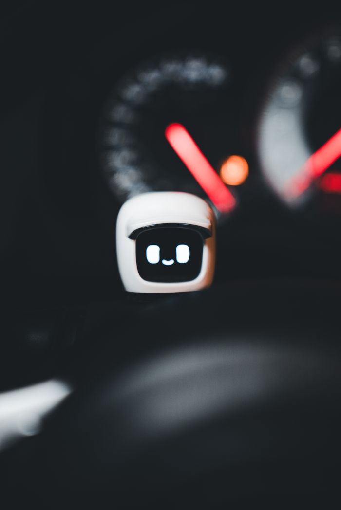 A cute digital gadget with a smiling face in a car interior, highlighting technology integration.