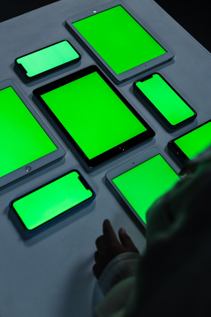 our-experience A variety of digital devices with green screens arranged on a table indoors.